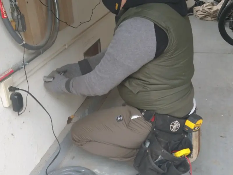 Electrician performing outlet wiring in a Howard garage